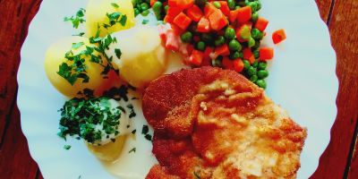 Paniertes Kotelett mit Petersilienkartoffeln Erbsen und Mrchen und heller Soe